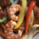 Illustration of Virginia's Shrimp and Grits with three cooked shrimp, sliced sausage, red, yellow and green sliced peppers.
