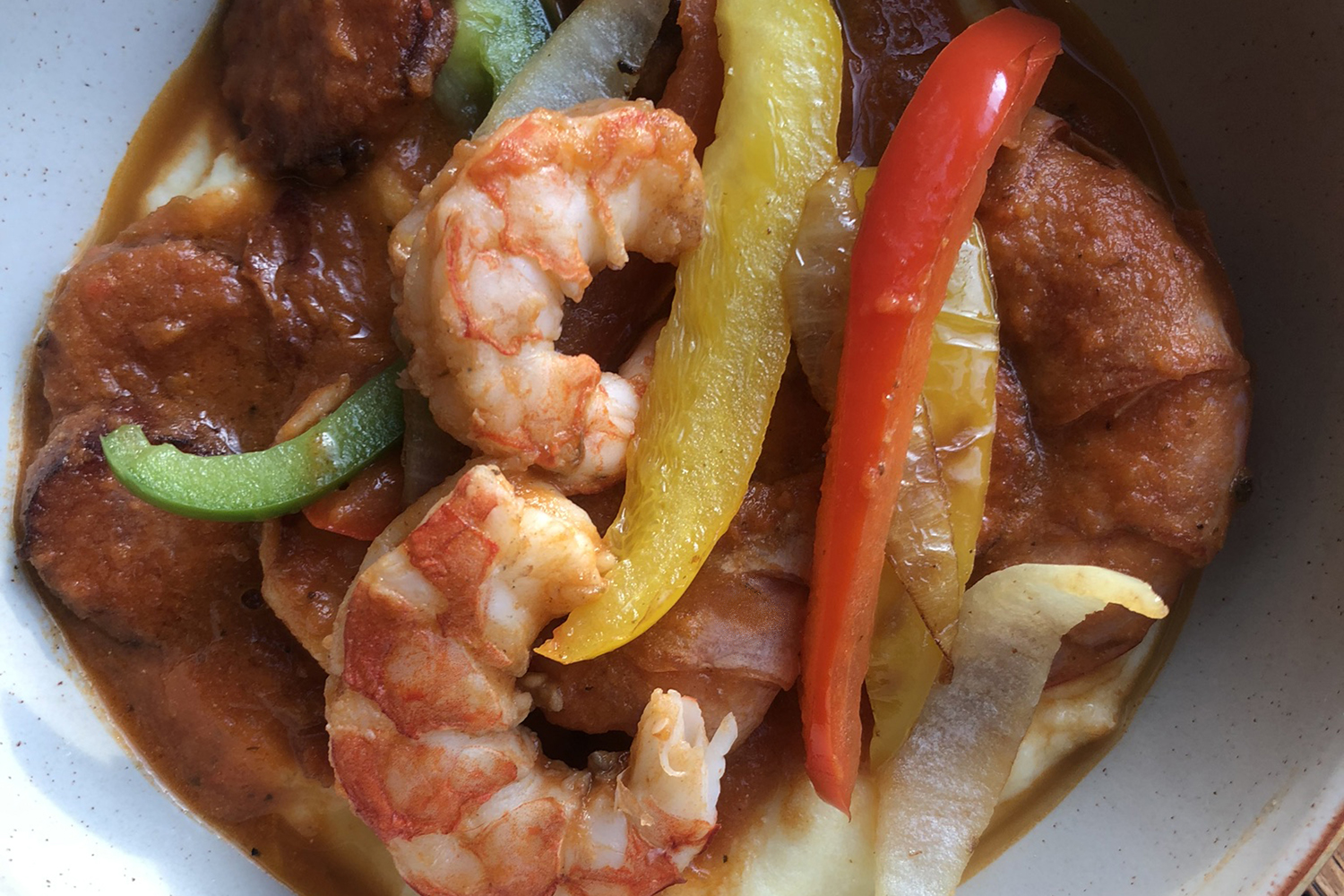 Illustration of Virginia's Shrimp and Grits with three cooked shrimp, sliced sausage, red, yellow and green sliced peppers.
