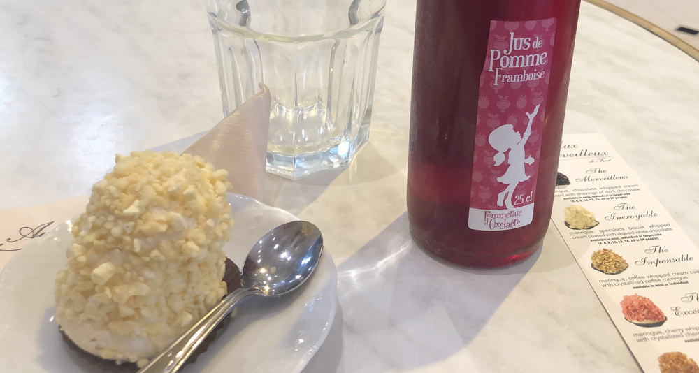 meringue pastry on a plate with a spoon and a bottle of raspberry-apple juice