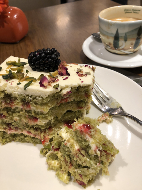 Pistachio cake - green layered cake with cream cheese frosting and a black berry on top