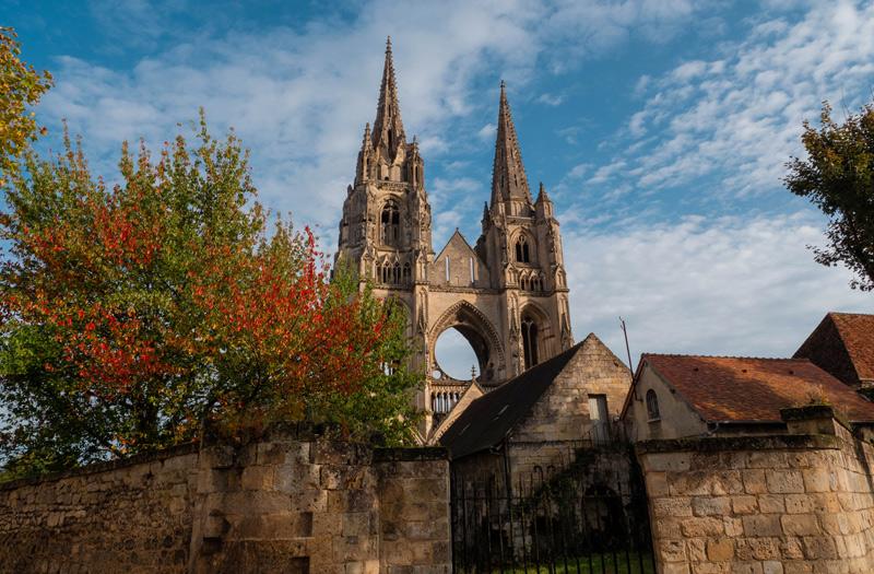 Towers of an abbey framed by blue skies and autumn leaves