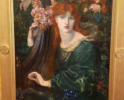 Victorian portrait of a red haired woman dressed in green, holding a harp and garlanded withflowers