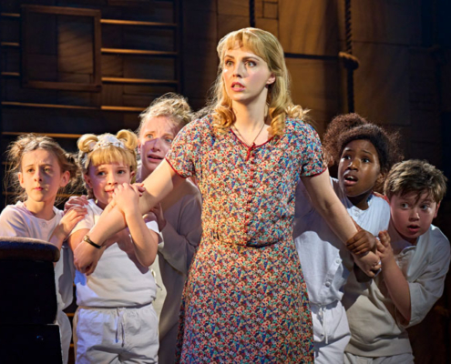 Eve Norris as Miss Honey and children of the ensemble.